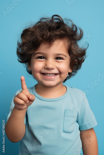 Delighted toddler giving a peace sign, against a serene blue studio background