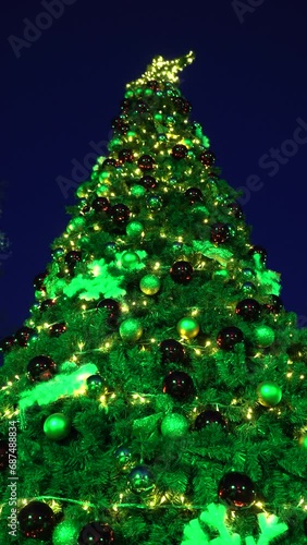 Closeup of beautiful shiny Christmas tree illuminated by colorful lighting.	