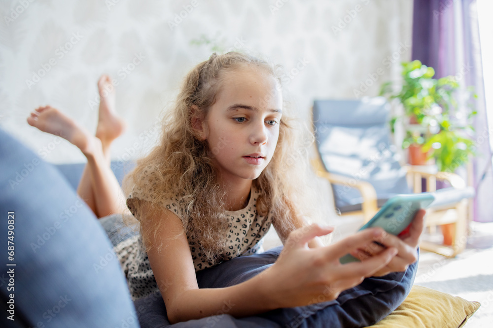 A cute teenage girl is immersed in studying the Internet and reading messages on her smartphone. A cute teenage girl is immersed in studying the Internet and reading messages on her smartphone.