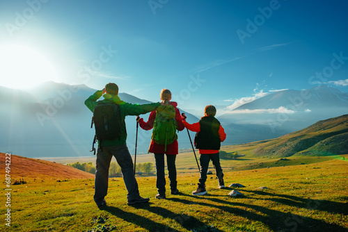Hiking family in the mountains on a sunny day at autumn, backside view