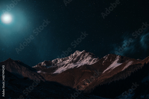 Night view of snowy mountain peaks in the light of moon and stars photo