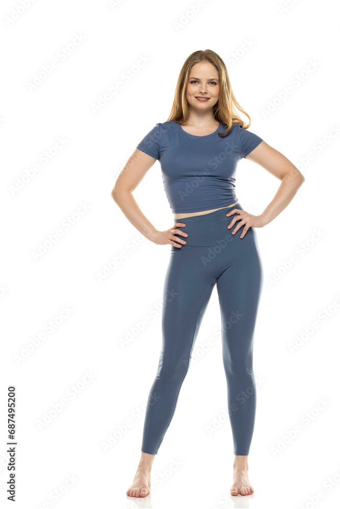 Full body, front view young smiling woman in sportswear posing on white background