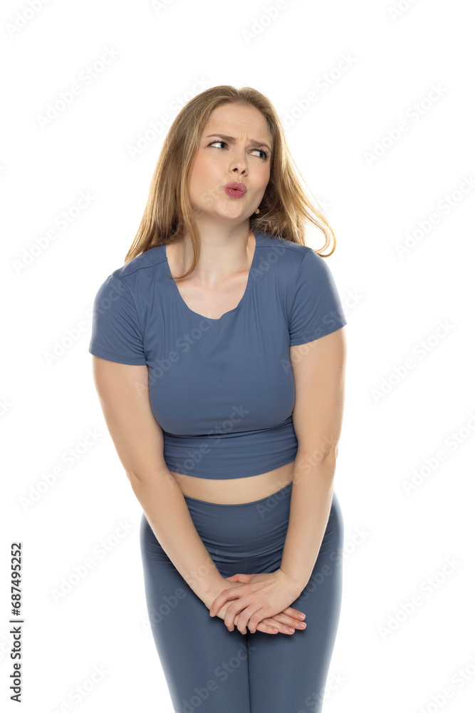 Young blond woman in sportswear pressing her crotch lower abdomen with her hands. Medical or gynecological problems, healthcare concept. Young blond woman in sportswear pressing her crotch lower abdomen with her hands. Medical or gynecological problems, healthcare concept.