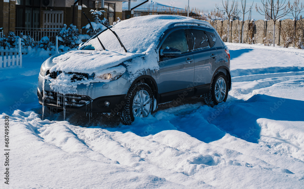 Snow covered and icy car near country house in cold winter