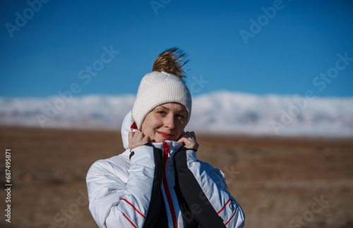 Portrait of happy young woman tourist on mountains background in windy winter day © chaossart