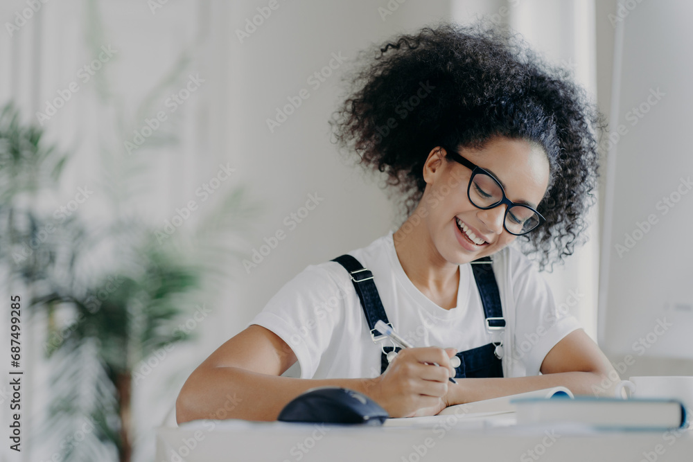 Joyful young student writing in notebook with a bright smile Joyful young student writing in notebook with a bright smile