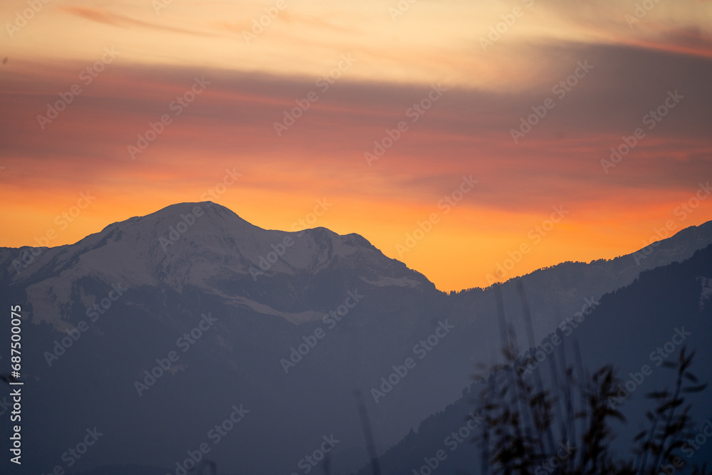 Sunrise sunset dusk dawn colors over the himalaya mountains with fog haze in distance with rich orange and red colors in manali kullu shimla