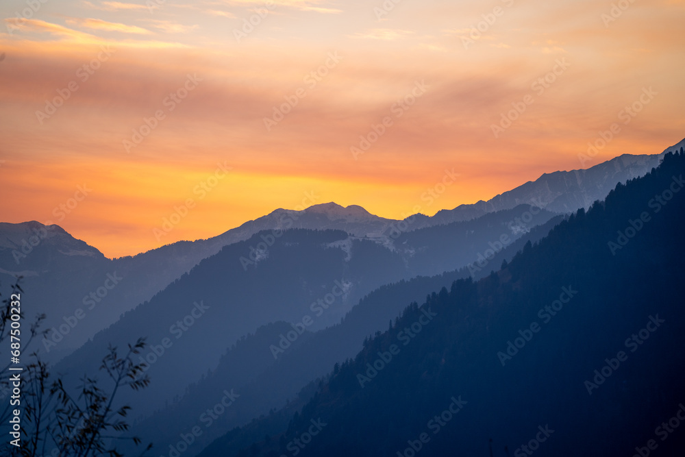 Sunrise sunset dusk dawn colors over the himalaya mountains with fog haze in distance with rich orange and red colors in manali kullu shimla
