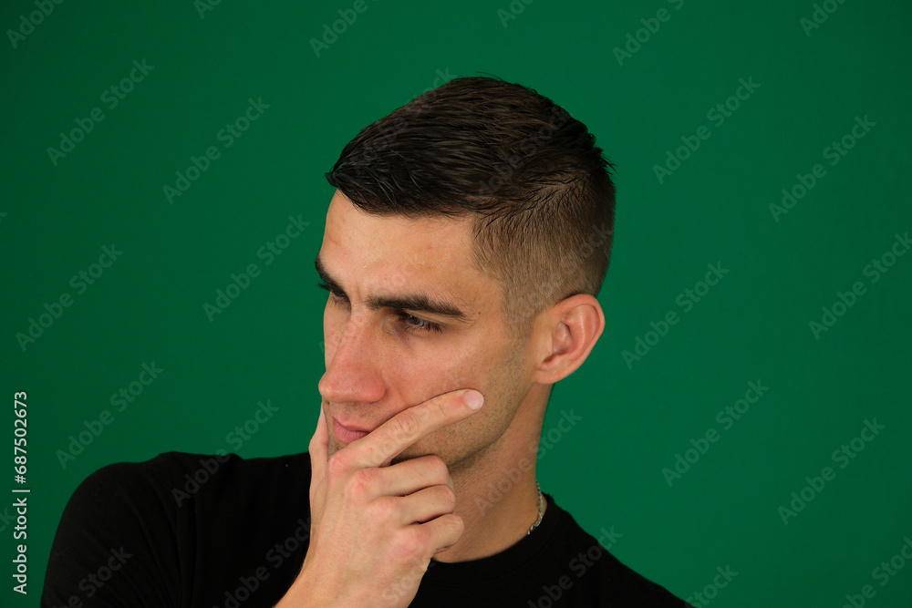 young guy lost in thought, supports his head with his hand, squints his eyes, gazes intently, black T-shirt, light stubble, macho, ponders thoughts. emotions of a handsome man young guy lost in thought, supports his head with his hand, squints his eyes, gazes intently, black T-shirt, light stubble, macho, ponders thoughts. emotions of a handsome man