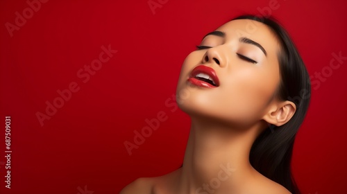 Pretty brunette young Asian woman closes eyes licks lipsfrom temptation to taste something delicious shows tongue imagines eating delicious food wears shirt isolated over vivid red bac : Generative AI photo