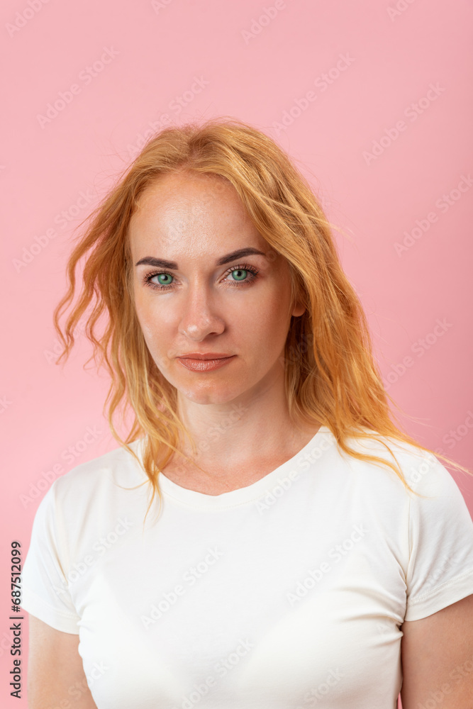 Portrait of beautiful young woman looking in the camera. Girl with ginger wavy hair and green eyes. Pink background, vertical frame Portrait of beautiful young woman looking in the camera. Girl with ginger wavy hair and green eyes. Pink background, vertical frame