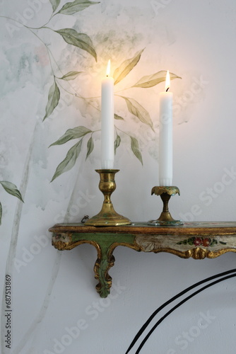 two candles in vintage candlesticks on a shelf