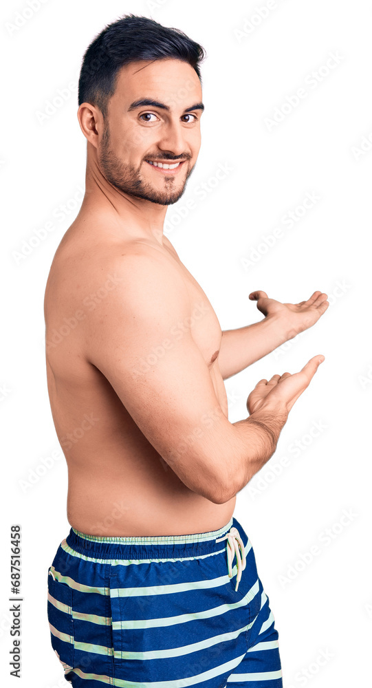 Fototapeta premium Young handsome man wearing swimwear inviting to enter smiling natural with open hand