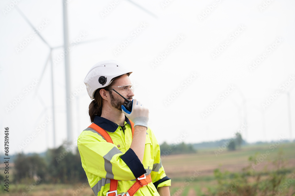Male engineer using radio communication at windmill field farm. Male engineer working at at wind turbines farm