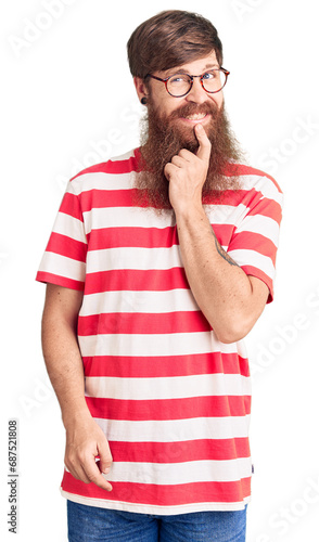 Handsome young red head man with long beard wearing casual clothes looking confident at the camera with smile with crossed arms and hand raised on chin. thinking positive.