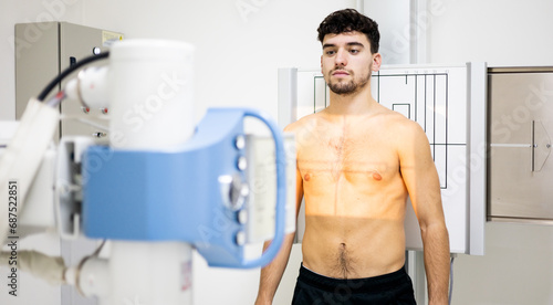 A young Caucasian man undergoes a chest x-ray test inside a hospital to detect cancer, infection or chronic lung diseases.Concept of chest MRIs.