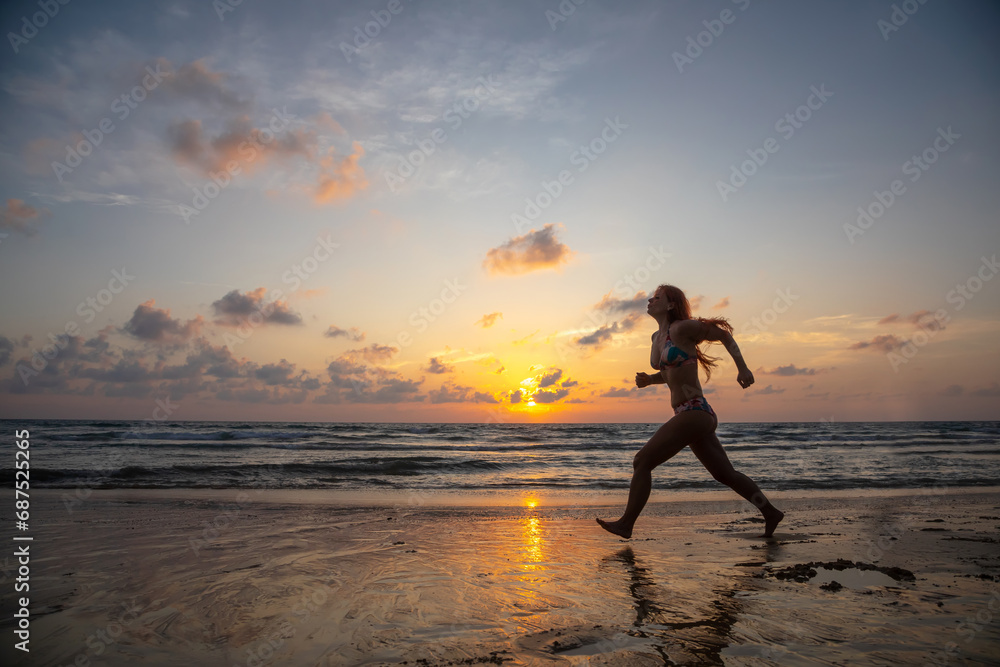A beautiful girl in a swimsuit jumps at sunset. Sunny colorful sunset. Seashore on the beach. A beautiful girl in a swimsuit jumps at sunset. Sunny colorful sunset. Seashore on the beach.