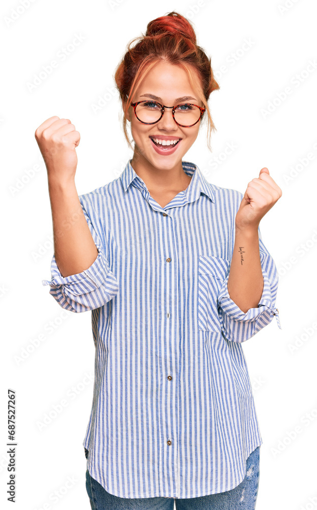 Young redhead woman wearing casual clothes and glasses screaming proud, celebrating victory and success very excited with raised arms Young redhead woman wearing casual clothes and glasses screaming proud, celebrating victory and success very excited with raised arms