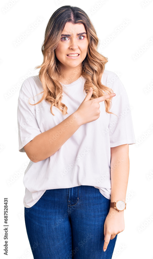 Young caucasian woman wearing casual clothes pointing aside worried and nervous with forefinger, concerned and surprised expression Young caucasian woman wearing casual clothes pointing aside worried and nervous with forefinger, concerned and surprised expression