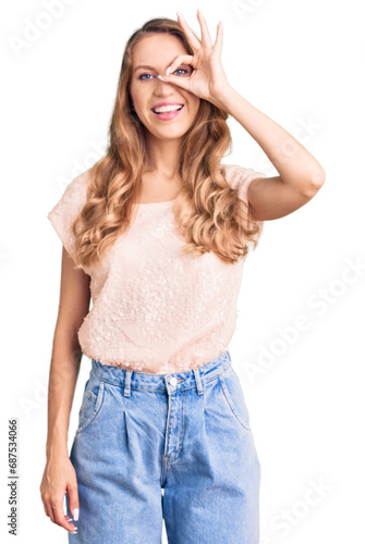 Young beautiful caucasian woman with blond hair wearing casual clothes doing ok gesture with hand smiling, eye looking through fingers with happy face.