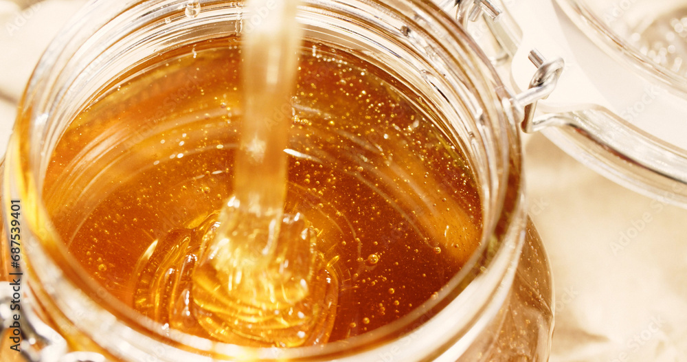Closeup shot of organic homemade honey in a glass jar under bright sunlight Closeup shot of organic homemade honey in a glass jar under bright sunlight