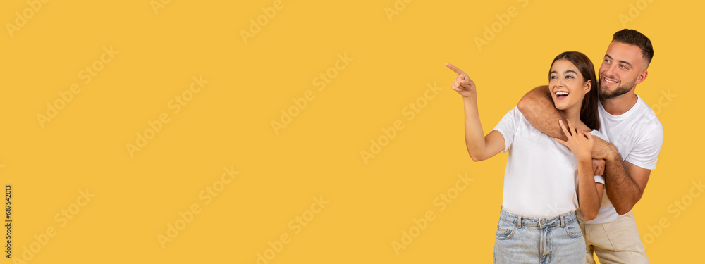 Laughing millennial european woman in white t-shirt point finger to guy at copy space - obrazy, fototapety, plakaty 