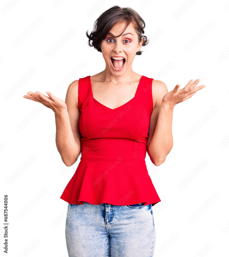 Beautiful young woman with short hair wearing casual style with sleeveless shirt celebrating crazy and amazed for success with arms raised and open eyes screaming excited. winner concept Beautiful young woman with short hair wearing casual style with sleeveless shirt celebrating crazy and amazed for success with arms raised and open eyes screaming excited. winner concept