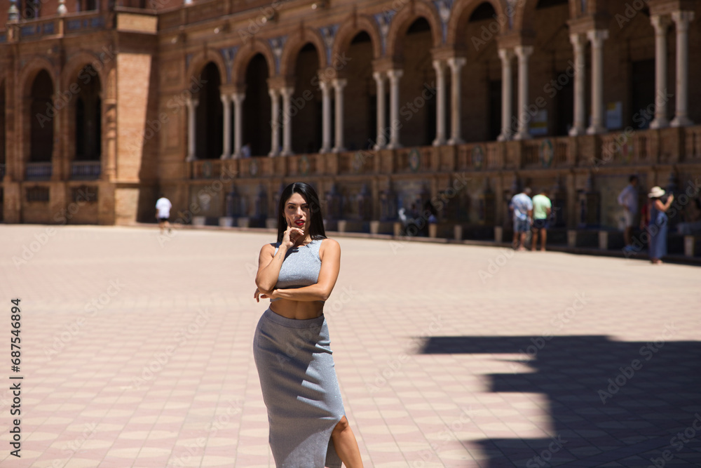 Latin woman, young and beautiful brunette is posing in a famous square in seville known internationally all over the world. The woman is having fun on her holidays in europe.