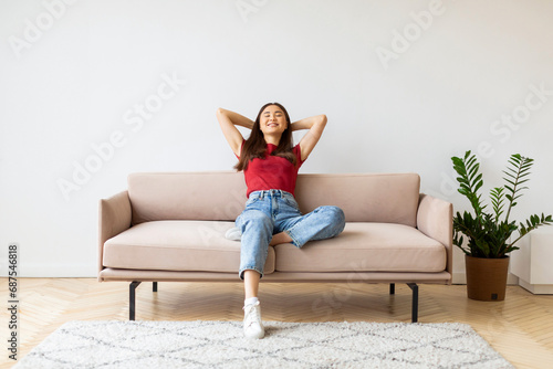 Home Comfort. Portrait Of Smiling Young Asian Woman Leaning Back On Couch