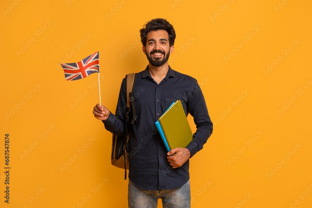 Language Courses. Smiling Young Indian Man Holding British Flag And Workbooks - obrazy, fototapety, plakaty 