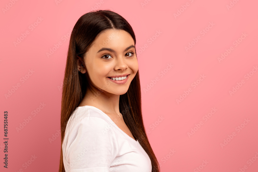 Attractive teen girl with beautiful smile looking over her shoulder at camera Attractive teen girl with beautiful smile looking over her shoulder at camera
