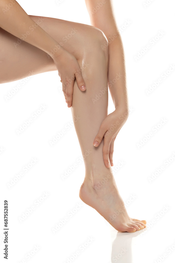 Young woman applies cosmetic product on her legs on white background. Young woman applies cosmetic product on her legs on white background.