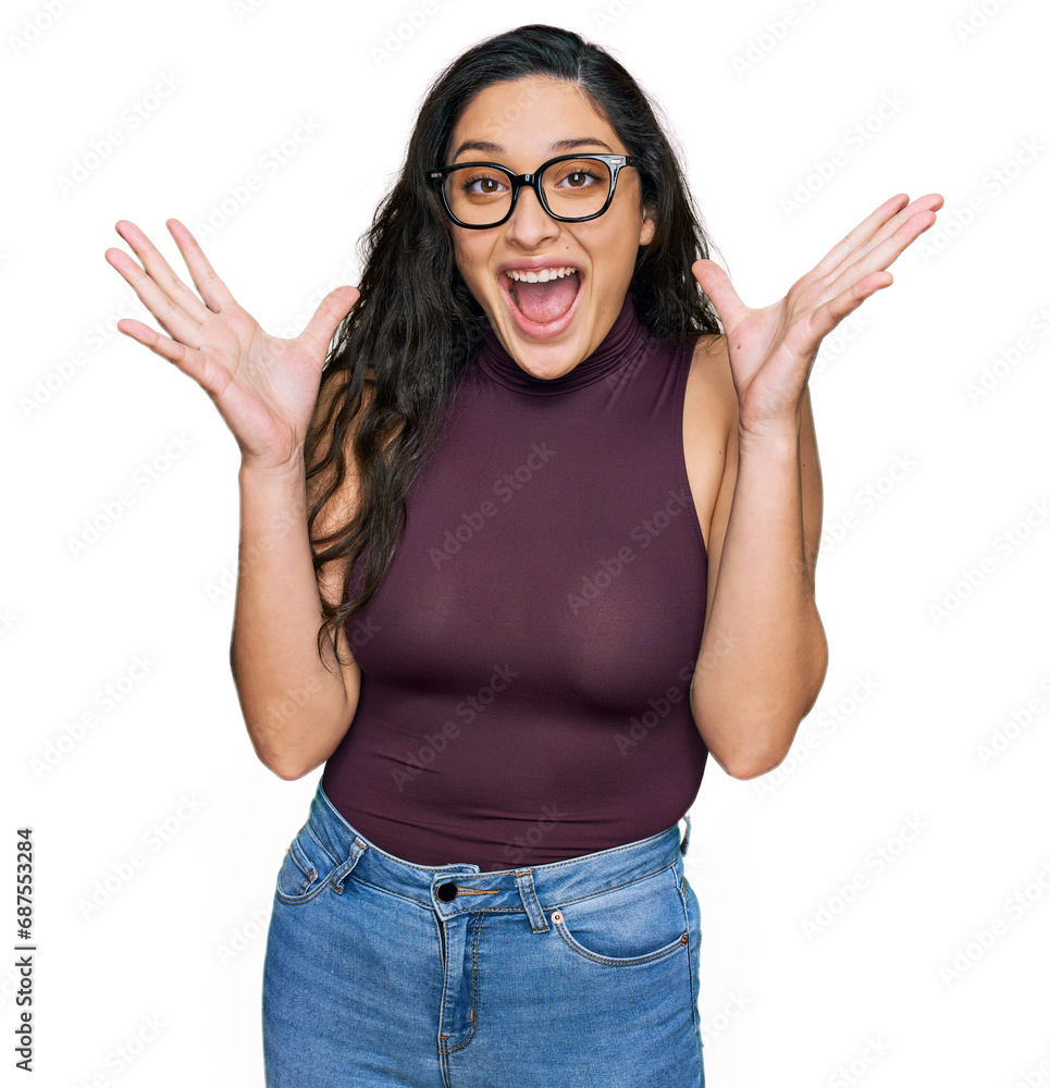 Brunette young woman wearing casual clothes and glasses celebrating crazy and amazed for success with arms raised and open eyes screaming excited. winner concept Brunette young woman wearing casual clothes and glasses celebrating crazy and amazed for success with arms raised and open eyes screaming excited. winner concept