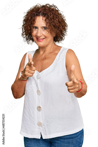 Beautiful middle age mature woman wearing casual white shirt pointing fingers to camera with happy and funny face. good energy and vibes.
