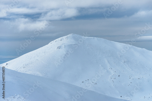 Peak of the Mountain. Beautiful landscape on the cold winter day. View of high mountains with snow white peaks and trees in the snow drifts.