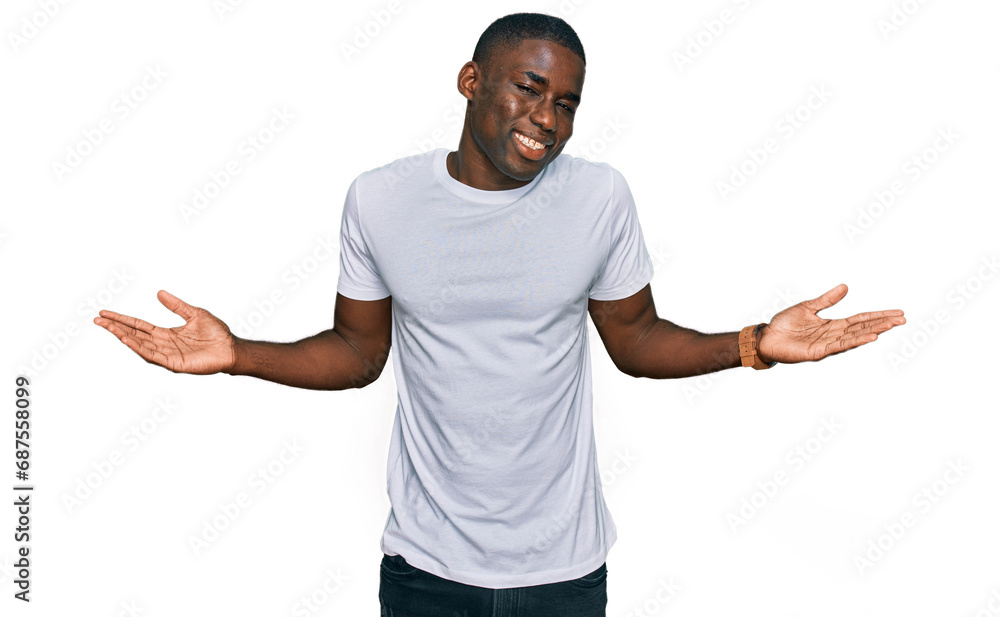 Young african american man wearing casual white t shirt smiling showing both hands open palms, presenting and advertising comparison and balance Young african american man wearing casual white t shirt smiling showing both hands open palms, presenting and advertising comparison and balance
