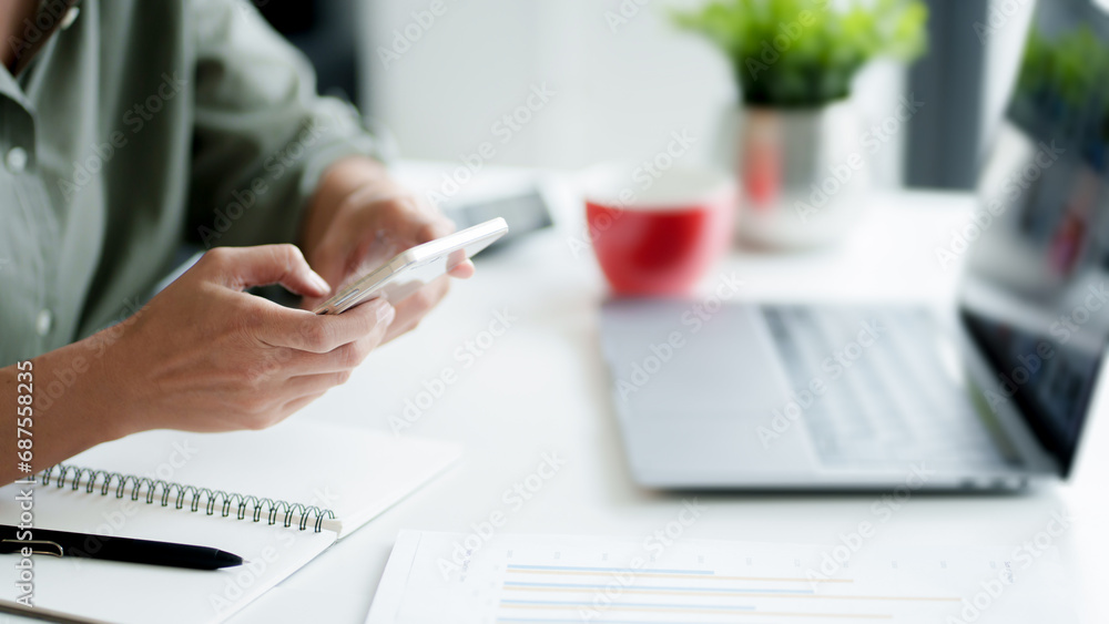 Fototapeta premium Businesswoman use smartphone and laptop with technology to working about calculation tax in office..