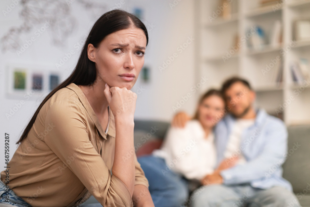 couple embraces while unhappy young lady looking at camera indoor couple embraces while unhappy young lady looking at camera indoor