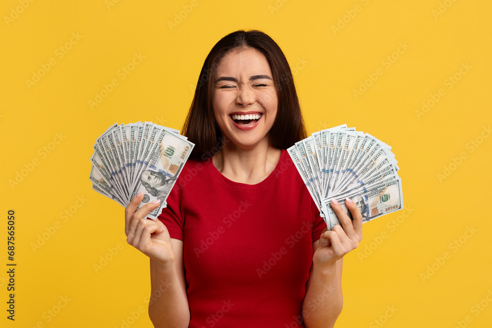 Happy emotional asian woman holding bunch of money banknotes Happy emotional asian woman holding bunch of money banknotes