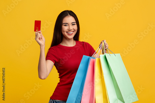 Happy young asian lady with shopping bags and credit card