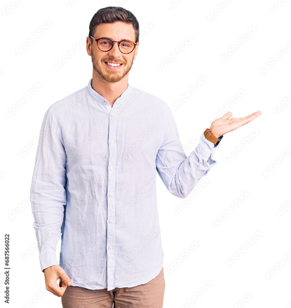 Handsome young man with bear wearing elegant business shirt and glasses smiling cheerful presenting and pointing with palm of hand looking at the camera. Handsome young man with bear wearing elegant business shirt and glasses smiling cheerful presenting and pointing with palm of hand looking at the camera.