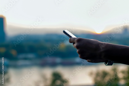Close up view of female hands using smartphone near the river during sunset