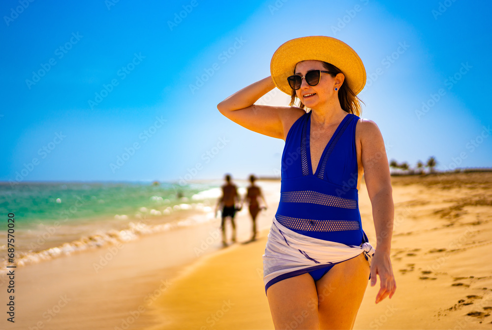 Beautiful woman walking on sunny beach Santa Maria, Sal Island, Cape Verde 