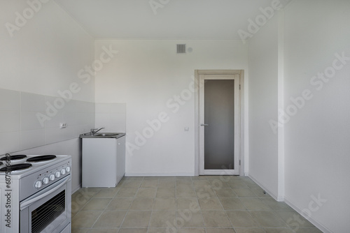 Kitchen with electric stove and sink after renovation. Kitchen in a new economy segment apartment without furniture