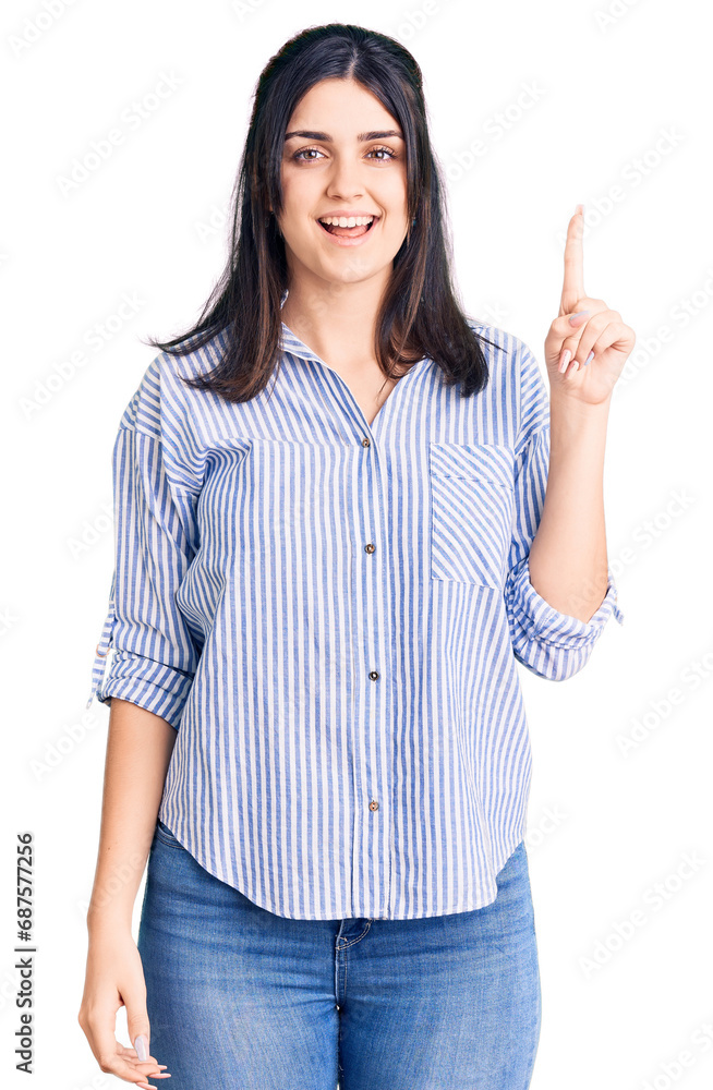 Young beautiful girl wearing striped shirt pointing finger up with successful idea. exited and happy. number one. Young beautiful girl wearing striped shirt pointing finger up with successful idea. exited and happy. number one.