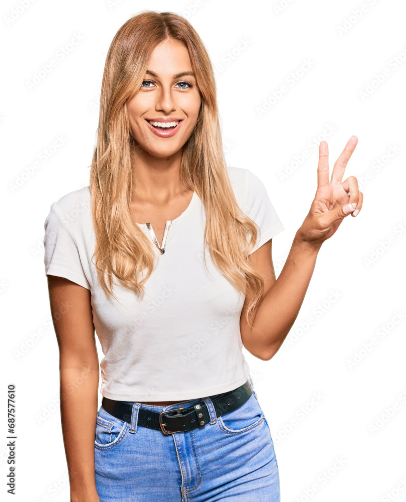Beautiful blonde young woman wearing casual white tshirt showing and pointing up with fingers number two while smiling confident and happy.