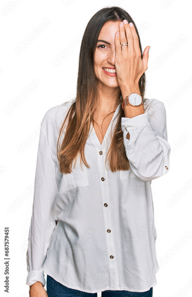 Young beautiful woman wearing casual clothes covering one eye with hand, confident smile on face and surprise emotion. Young beautiful woman wearing casual clothes covering one eye with hand, confident smile on face and surprise emotion.