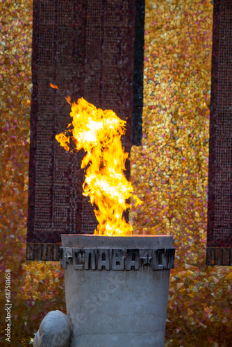 Close-up view of burning Eternal Flame in Volgograd city, Russia. Russian word on torch translation: Glory. Gold colored background. Theme of eternal memory of those who died for their homeland.