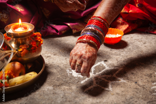 An Indian woman is making an Auspicious Hindu design pattern (rangoli) for the Karwa Chauth Festival. photo