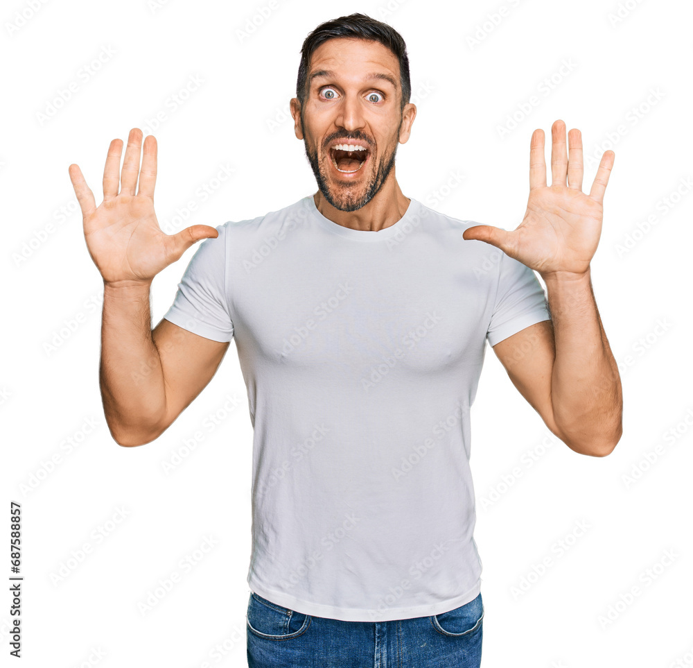 Handsome man with beard wearing casual white t shirt celebrating crazy and amazed for success with arms raised and open eyes screaming excited. winner concept Handsome man with beard wearing casual white t shirt celebrating crazy and amazed for success with arms raised and open eyes screaming excited. winner concept
